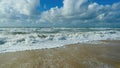 View over sand beach on waves in french atlantic ocean against clouds with blue sky - Soulac-sur-mer, Bretagne, France