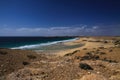 View over sand dunes with green ocean on Playa del Aljibe on white village on steep cliff El Cotillo - North Fuerteventura