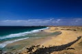 View over sand dunes with green ocean on Playa del Aljibe on white village on steep cliff El Cotillo - North Fuerteventura