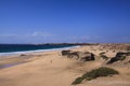 View over sand dunes with green ocean on Playa del Aljibe on white village on steep cliff El Cotillo - North Fuerteventura