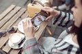 View over shoulder on woman taking photo with smartphone of coffee and cheesecake.