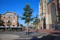 View over square on medieval gothic church entrance, green tree and restaurant cafe in city center