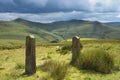 View over sunlit mountains and rock gate posts with dark clouds overhead, Peak District, UK Royalty Free Stock Photo