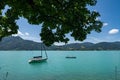 View over the turquoise Tegernsee with a paddeling couple and a boat, in the beautiful width of the alps mountains in