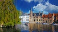 View over water canal on pier with tourist sightseeing boats, medieval buildings, green tree against clear blue autumn sky Royalty Free Stock Photo