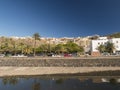 View over a water channel on a street in the center of San Sebastian de la Gomera with colorful houses, palm trees and