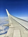 View over the Wing of a Passenger Aircraft from High Altitude on the Clouds in the Blue Sky beneath the Aircraft Royalty Free Stock Photo