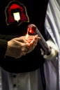 Hands lighting a religious style long candle held by a gloved hand