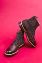 View of Pair of Premium Dark Brown Grain Brogue Derby Boots Made of Calf Leather with Rubber Sole Placed On Pink