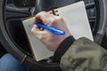 View of paper notebook for notes in the hands of a car driver