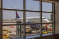 View of parked Delta aircraft from inside of airport through window. USA.