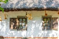 View of a part of the facade of an old Ukrainian rural hut with old windows under a thatched roof Royalty Free Stock Photo