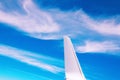 View of the part of a wing of an aeroplane or airliner in flight out of the window with blue sky and light clouds. Wing of Royalty Free Stock Photo