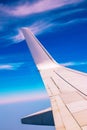 View of the part of a wing of an aeroplane or airliner in flight out of the window with blue sky and light clouds. Wing of Royalty Free Stock Photo