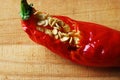 PARTIALLY EATEN RED CHILI ON A WOODEN BOARD