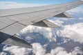 View from passenger window of commercial airplane, clouds on blue sky visible under aircraft wing Royalty Free Stock Photo