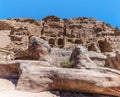 A view past striped rock formations towards the Royal Tombs in the ancient city of Petra, Jordan Royalty Free Stock Photo
