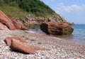 A view of the pebbled beach and red rocks at Oddicombe