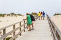 View of pedestrian path on beach, backs of couple with daughter walking on wooden path and other couple talking