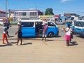 View of a people selling things on the street, typical blue van taxi, road with cars, people and difficulties as a background