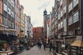 View of people walking in Gdansk's old town street with medieval architecture under the cloudy sky