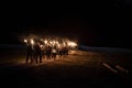 View of people walking with torches in a dark street during the night Royalty Free Stock Photo