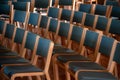 View of perfectly aligned empty wooden chairs on a conference hall