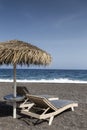 view of Perissa beach on the Greek island of Santorini with sunbeds and umbrellas. Beach is covered with fine black sand, and Royalty Free Stock Photo