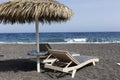 view of Perissa beach on the Greek island of Santorini with sunbeds and umbrellas. Beach is covered with fine black sand, and Royalty Free Stock Photo