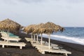 view of Perissa beach on the Greek island of Santorini with sunbeds and umbrellas. Beach is covered with fine black sand, and Royalty Free Stock Photo