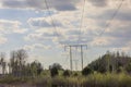 View of pillars high-voltage electric power transmission line against on blue sky with white clouds background. Royalty Free Stock Photo