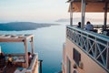 View of the pink-blue sunset on the island of Santorini to the sea, the sky and islands with people sitting back in a cafe in the