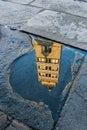 View of Pistoia Cathedral (Cattedrale di San Zeno) bell tower reflected in a puddle, Tuscany, Italy