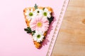 View of pizza slice with flowers on pink paper with cut out hearts on wooden table