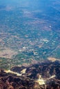 View from the plane window: from a great height below you can see mountains and green fields. Travel and tourism concept. Royalty Free Stock Photo