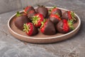 A view on a plate with dark chocolate covered strawberries on stone table. Isometric style Royalty Free Stock Photo