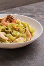 A view of a plate of Fettuccine pasta with shrimp, pesto sauce, walnut on white plate. Pasta seafood. Mediterranean cuisine