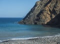 View of Playa de Vallehermoso, volcanic black sand beach with pebbles and mountain cliff with blue ocean and sky Royalty Free Stock Photo