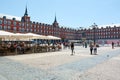 View of Plaza Mayor, the Main Square of Madrid. People walking and sculpture of the king Felipe III on a bright sunny spring day