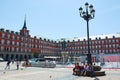 View of Plaza Mayor, the Main Square of Madrid. People walking and sculpture of the king Felipe III on a bright sunny spring day