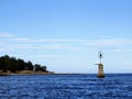 View of a port hand day beacon marking a reef hidden by the ocean at high tide.