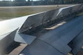 View from the porthole of an airplane wing taking off over the runway at high speed during sunset. The ground passes under the