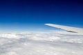 The wing of a flying plane against the background of thick white clouds. Royalty Free Stock Photo