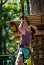 Portrait of a beautiful girl on a rope park among trees. Children summer activities.