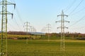 View of power lines in spring landscape with meadow and field, under blue sky Royalty Free Stock Photo