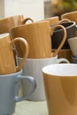 View on a quantity of empty coffee cups in different earthly colors. The mugs are standing on a table, ready to be filled