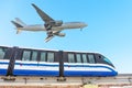 View railway track suburban electric monorail train rushing departure area airfield. Passenger plane jet flying sky, landing Royalty Free Stock Photo