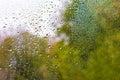 View of Rain drops on window with green,red and yellow color tree in background Autumn Abstract blurred Backdrop Royalty Free Stock Photo