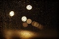 View through the rainy window at night with water drops and blurry city lights Royalty Free Stock Photo