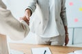 View of recruiter and employee shaking hands while standing in office